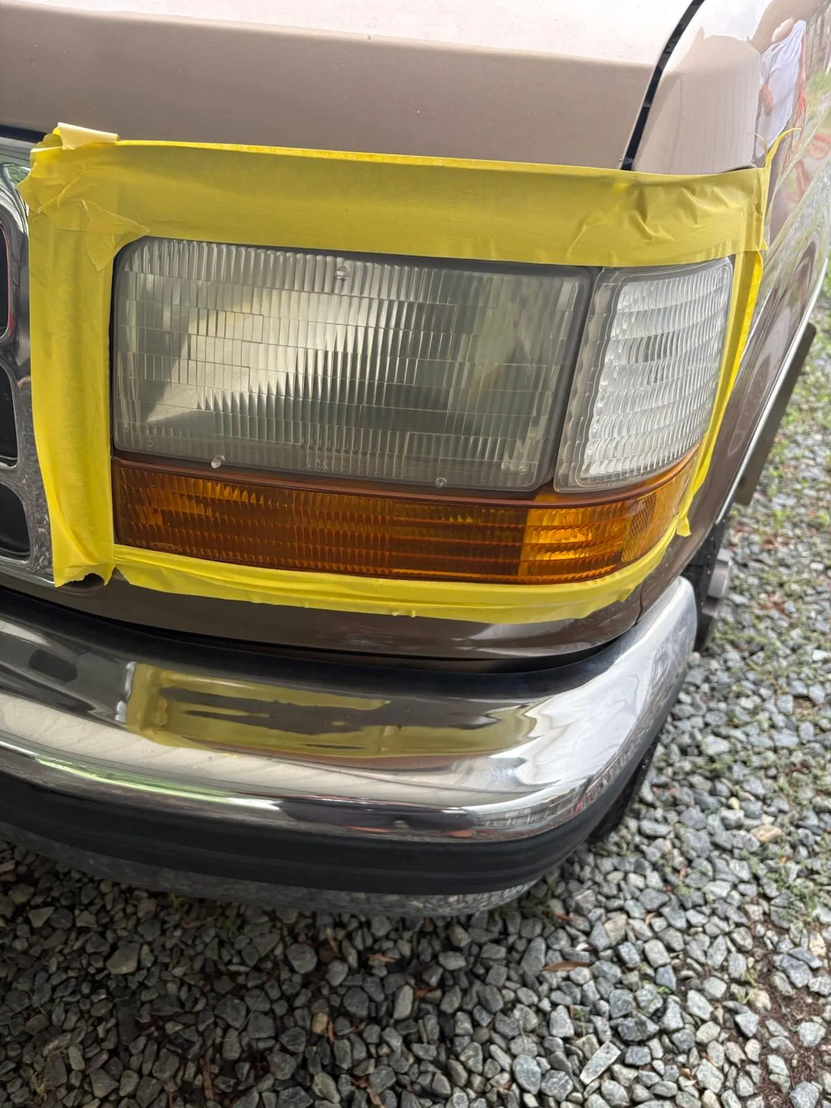 Masking tape applied around a headlight during professional headlight restoration in Lewisville, NC